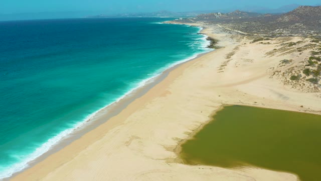 LA LAGUNA BEACH LOS CABOS MEXICO-2021: Waves Rolling Onto Sandy Beach Beside Lagoon