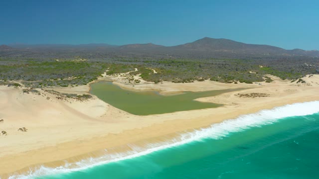 LA LAGUNA BEACH LOS CABOS MEXICO-2021: Waves Rolling In on Sandy Beach with Lagoon