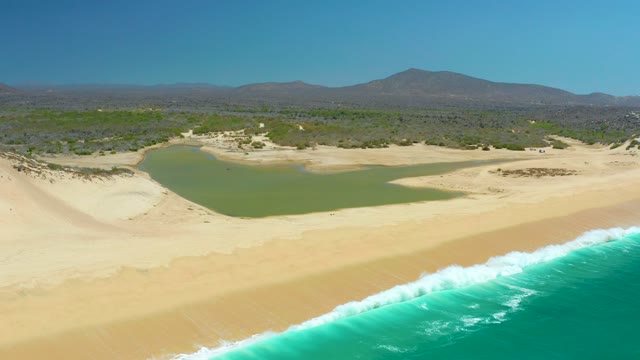 LA LAGUNA BEACH LOS CABOS MEXICO-2021: Waves Rolling Onto Sandy Beach with Lagoon