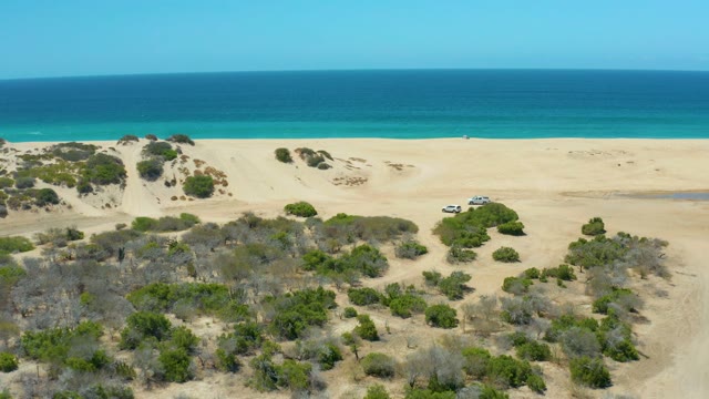 LA LAGUNA BEACH LOS CABOS MEXICO-2021: SUV Driving Across Coastal Sand Dunes by Ocean