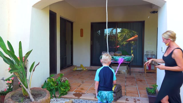 SAN JOSE DEL CABO BCS MEXICO-2020: Child and Adults Interacting with Hanging Piñata on Patio