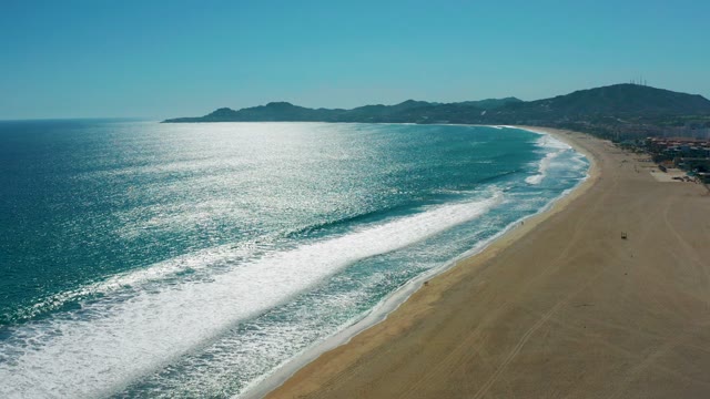 SAN JOSE DEL CABO MEXICO-2020: Waves Rolling Onto Sandy Shore with Distant Hills