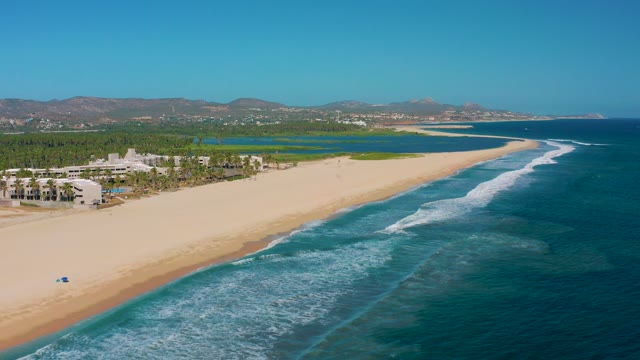 SAN JOSE DEL CABO MEXICO-2020: Sandy Beach with Gentle Ocean Waves and Coastal Buildings