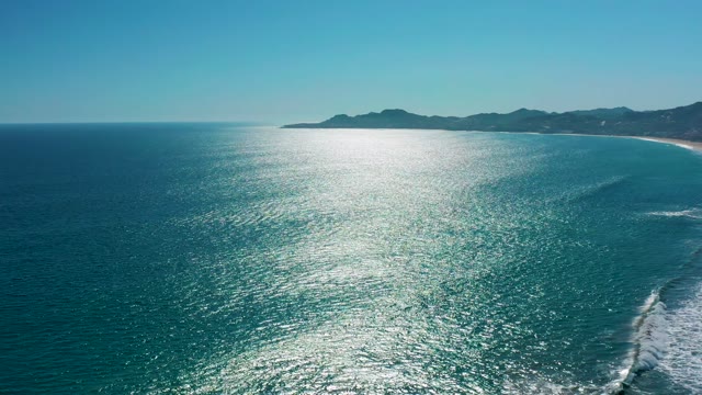 SAN JOSE DEL CABO MEXICO-2020: Waves Breaking on Sandy Beach with Mountain Backdrop