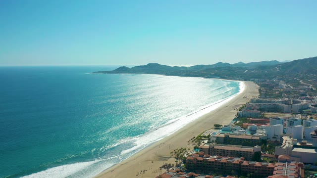 SAN JOSE DEL CABO MEXICO-2020: Sunny Coastal Beach with Ocean Waves and Buildings