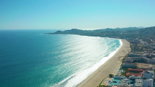 SAN JOSE DEL CABO MEXICO-2020: Waves Rolling Onto Sandy Beach with Coastal Buildings