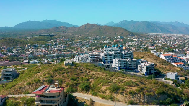 SAN JOSE DEL CABO MEXICO-2020: Aerial Pan of Hillside with Buildings and Distant Mountains