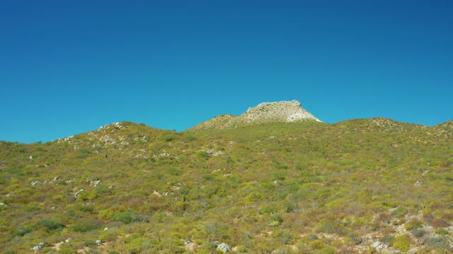 EAST CAPE BCS MEXICO-2020: Rocky Peak on a Grassy Mountain Slope Under Clear Sky