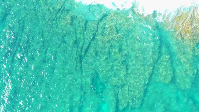 Clear Ocean Waves Breaking Over Rocky Seabed