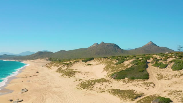 Car Driving on Sandy Beach with Dunes and Mountains