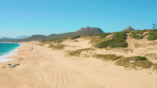 Vehicle Driving Along Sandy Beach with Dunes and Ocean