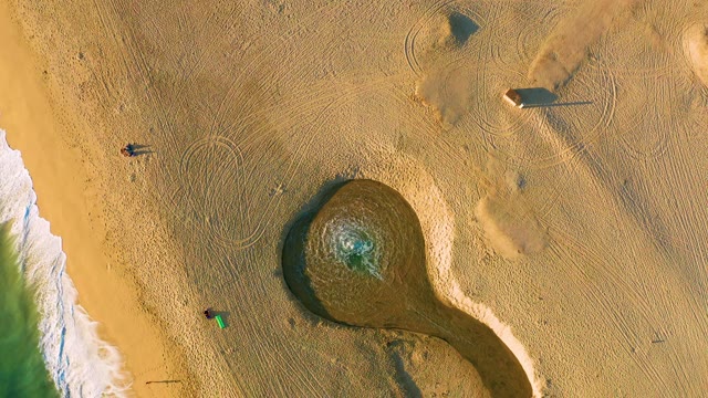 Two People Walking on Sandy Beach with Tidal Pool