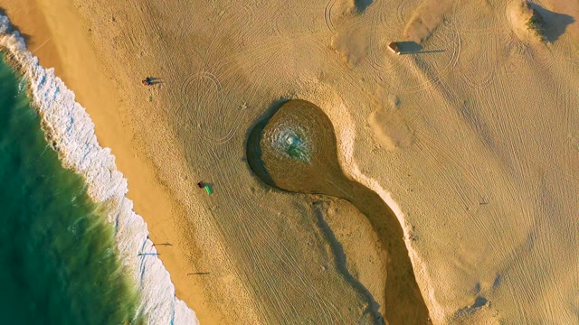 Waves Advancing on Sandy Beach with People Walking