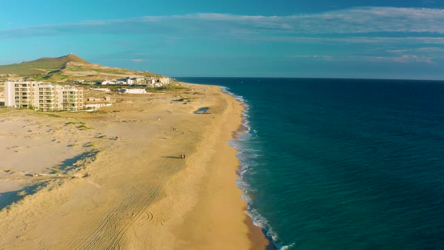 Person Strolling Along Sandy Beach with Ocean Waves