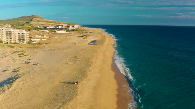 People Walking Along Sandy Beach by Ocean