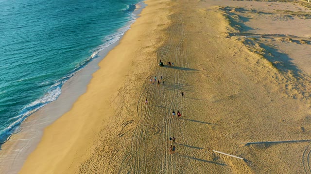 People Strolling Along a Sandy Beach near the Ocean