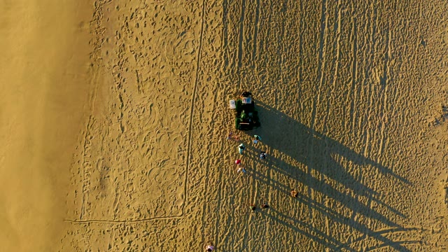 Beach Cart with People Moving Along Sandy Shore