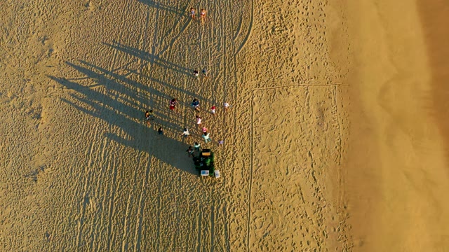 Group of People and Vehicle on Sandy Beach