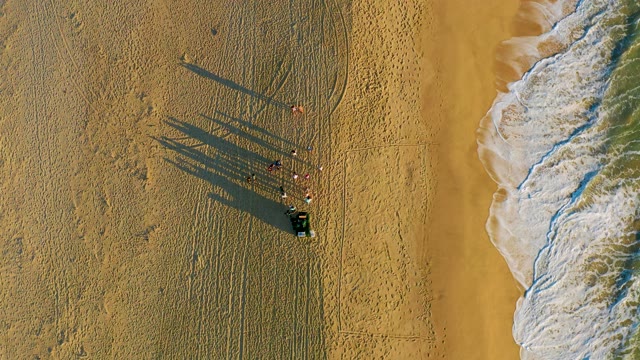 Group of People and Cart on Beach with Moving Waves