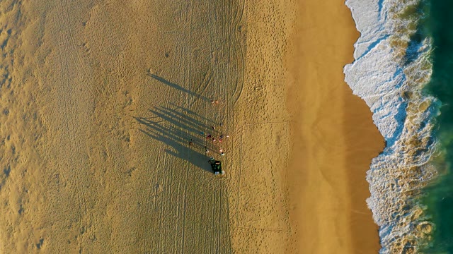 Beachgoers Standing As Ocean Waves Roll In