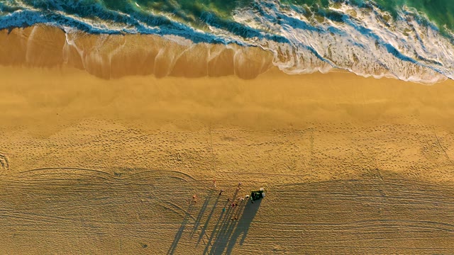 Ocean Waves Receding on Sandy Beach with Vehicle