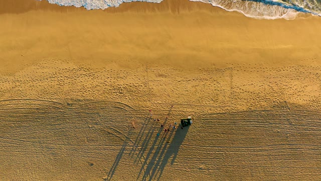 Sandy Beach with Receding Tide, People, and Vehicle