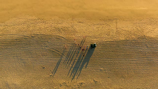 People and Vehicle on Sandy Beach As Ocean Appears