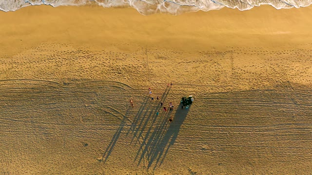Beachgoers and Vehicle on Sand with Advancing Ocean Waves