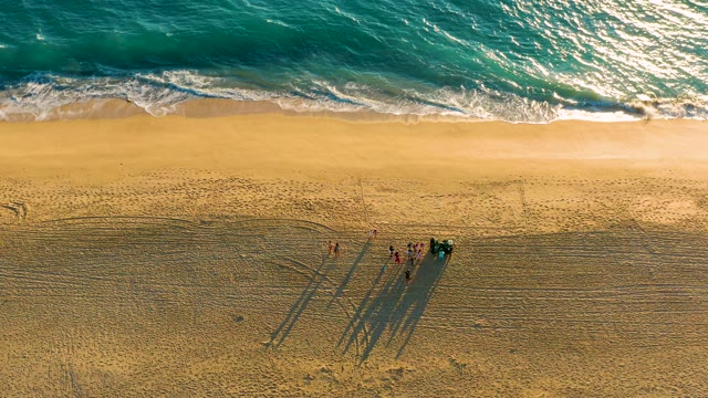 Group of People on Sandy Beach with Advancing Waves