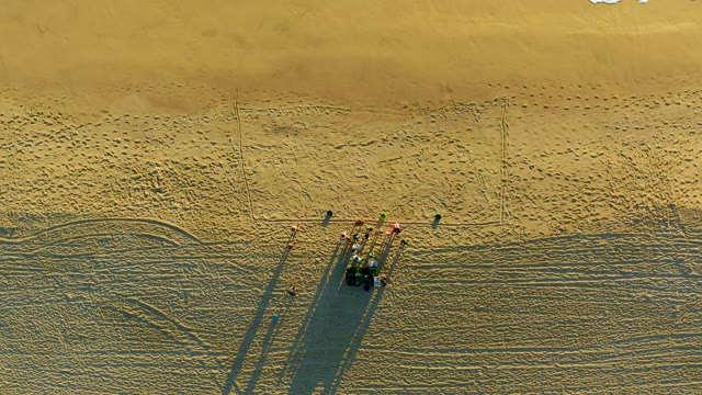 People Gathering Around Vehicle on Sandy Beach