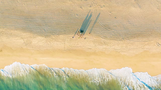 People's Shadows on Sandy Beach with Ocean Waves