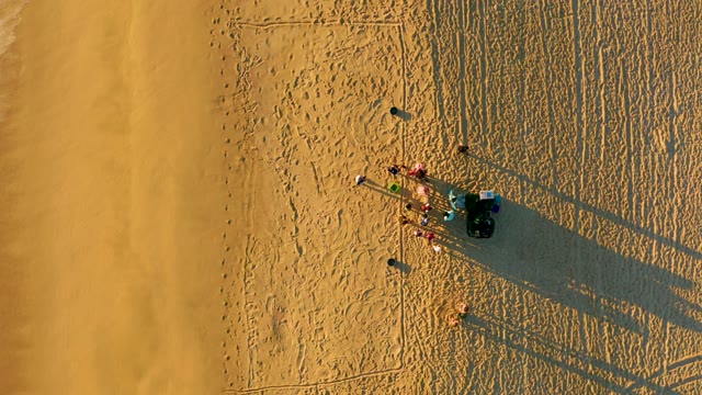 Group of People on Sandy Beach As Wave Approaches