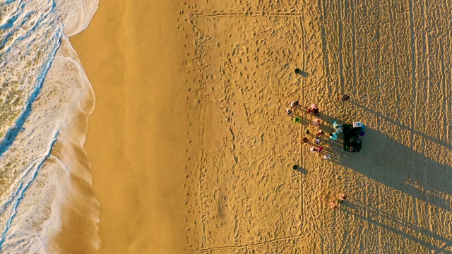 Receding Ocean Waves on Sandy Beach with People