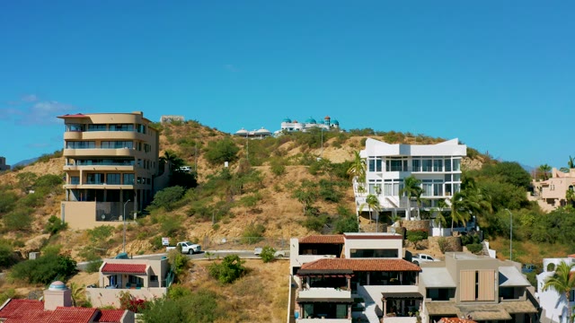 SAN JOSE DEL CABO BCS MEXICO-2020: Vehicles Traveling on a Hillside Road with Residential Buildings