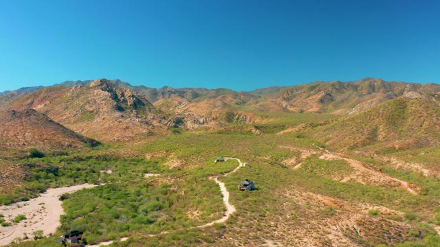 CABO PULMO BCS MEXICO-2020: Two SUVs Driving on a Winding Dirt Road Through Hilly Terrain