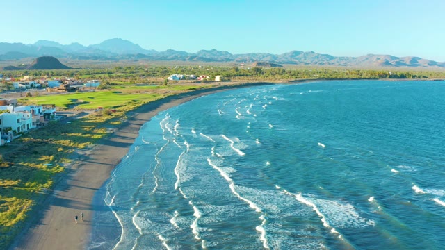 LORETO BCS MEXICO-2020: A Person Walking Along a Curved Beach with Ocean Waves