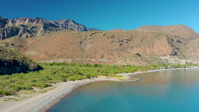 JUNCALITO BCS MEXICO-2020: Vehicle Moving Along Sandy Beach with Mountain Backdrop