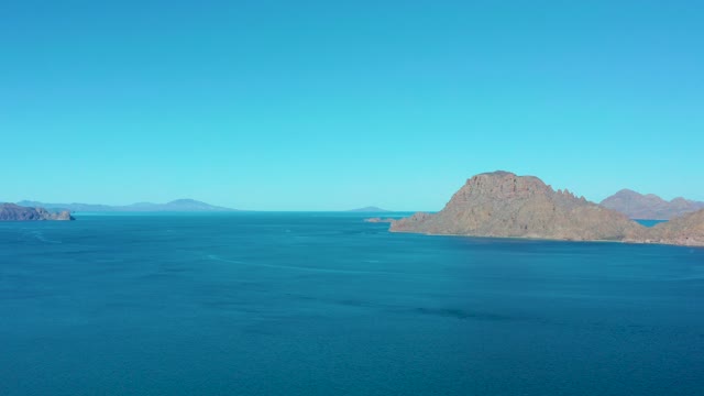 LIGUI BCS MEXICO-2020: Boat Moving Across Calm Blue Sea with Rocky Islands