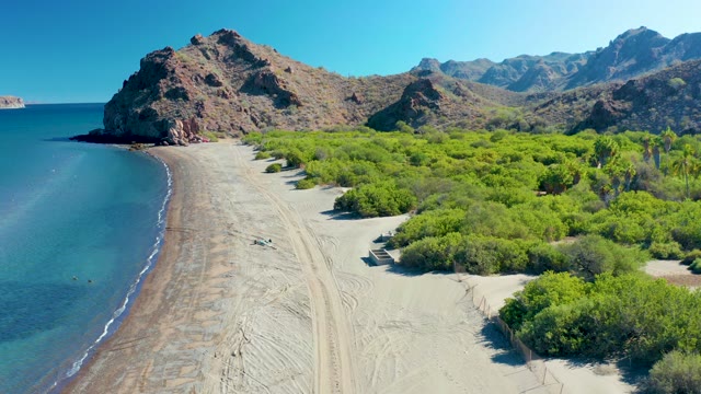 LIGUI BCS MEXICO-2020: Vehicle Moving Along Sandy Beach with Ocean and Greenery