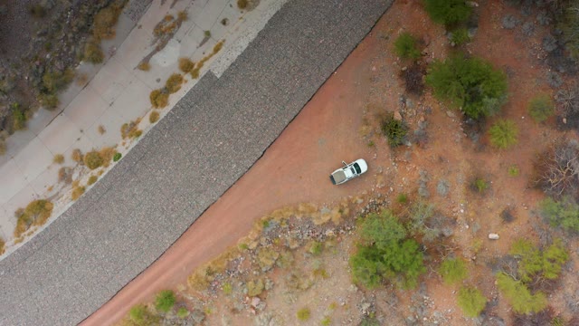 PUERTO ESCONDIDO BCS MEXICO-2020: White Car Moving on Red Dirt Road Beside Highway