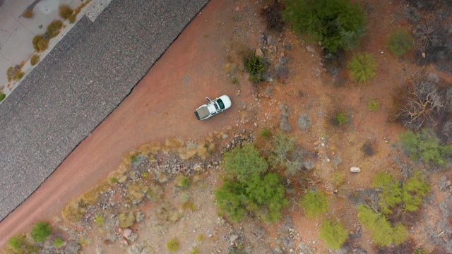 PUERTO ESCONDIDO BCS MEXICO-2020: White Car Moving on Red Dirt Road in Arid Terrain