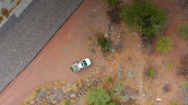 PUERTO ESCONDIDO BCS MEXICO-2020: White Car Moving on Dry Dirt Path Beside Paved Road