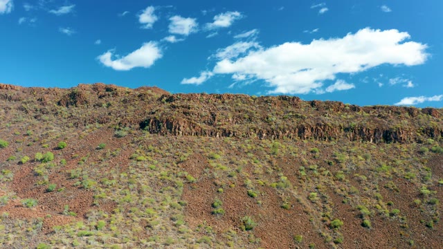 SAN JAVIER BCS MEXICO-2020: Reddish-brown Hillside with Scattered Green Shrubs and Clear Sky
