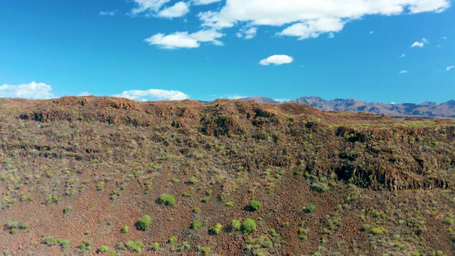 SAN JAVIER BCS MEXICO-2020: Red Rock Desert with Sparse Green Shrubs and Distant Mountains