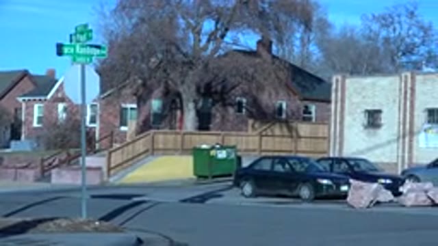 DENVER COLORADO-2015: Small Shop With Cars Parked in Front and a Black Car Passing