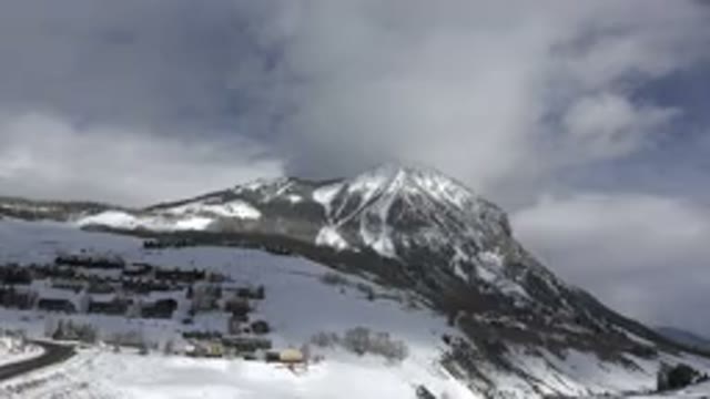 CRESTED BUTTE COLORADO-2015: Large Snowy Mountain Shot Pan Left With Clouds Near