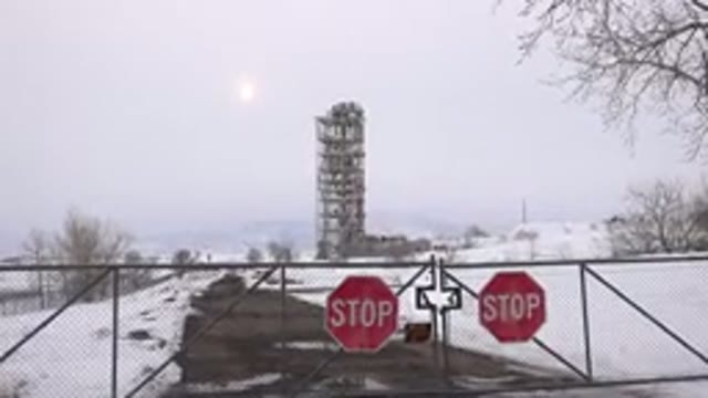ARVADA COLORADO-2015: Two Red Stop Signs And Grey Towering Object On A Cloudy