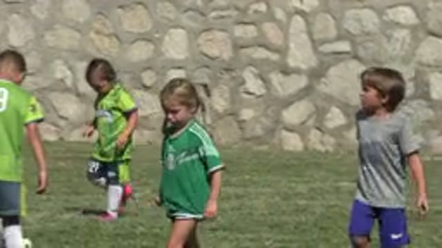 SAN JOSE DEL CABO MEXICO-2019: Kids Playing Soccer On Green Grass With Stone Wall