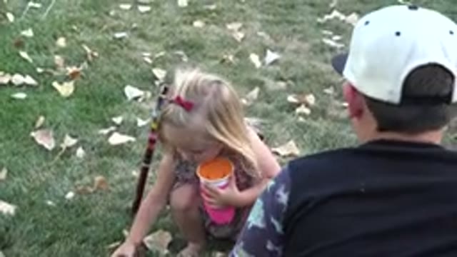 WESTMINSTER COLORADO-2016: Young Girl Holding A Pink Cup Picks Up A Ball And