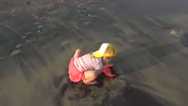GRAND JUNCTION COLORADO-2017: Girl in Cap Playing Sand with Pink Plastic Scoop at Sea